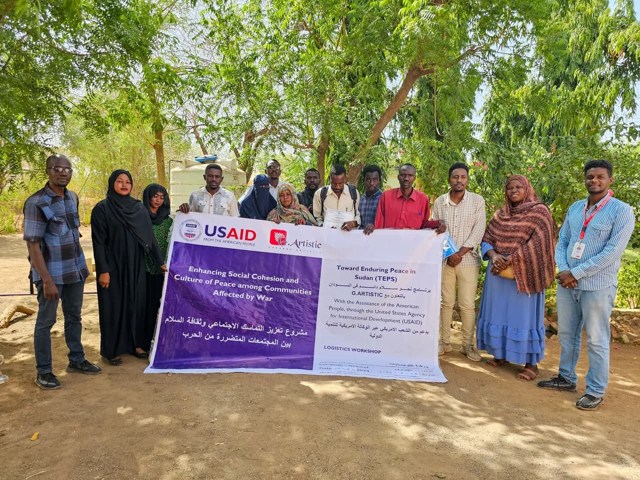 G.Artistic team members holding a banner for a donor-funded social cohesion project in Sudan.