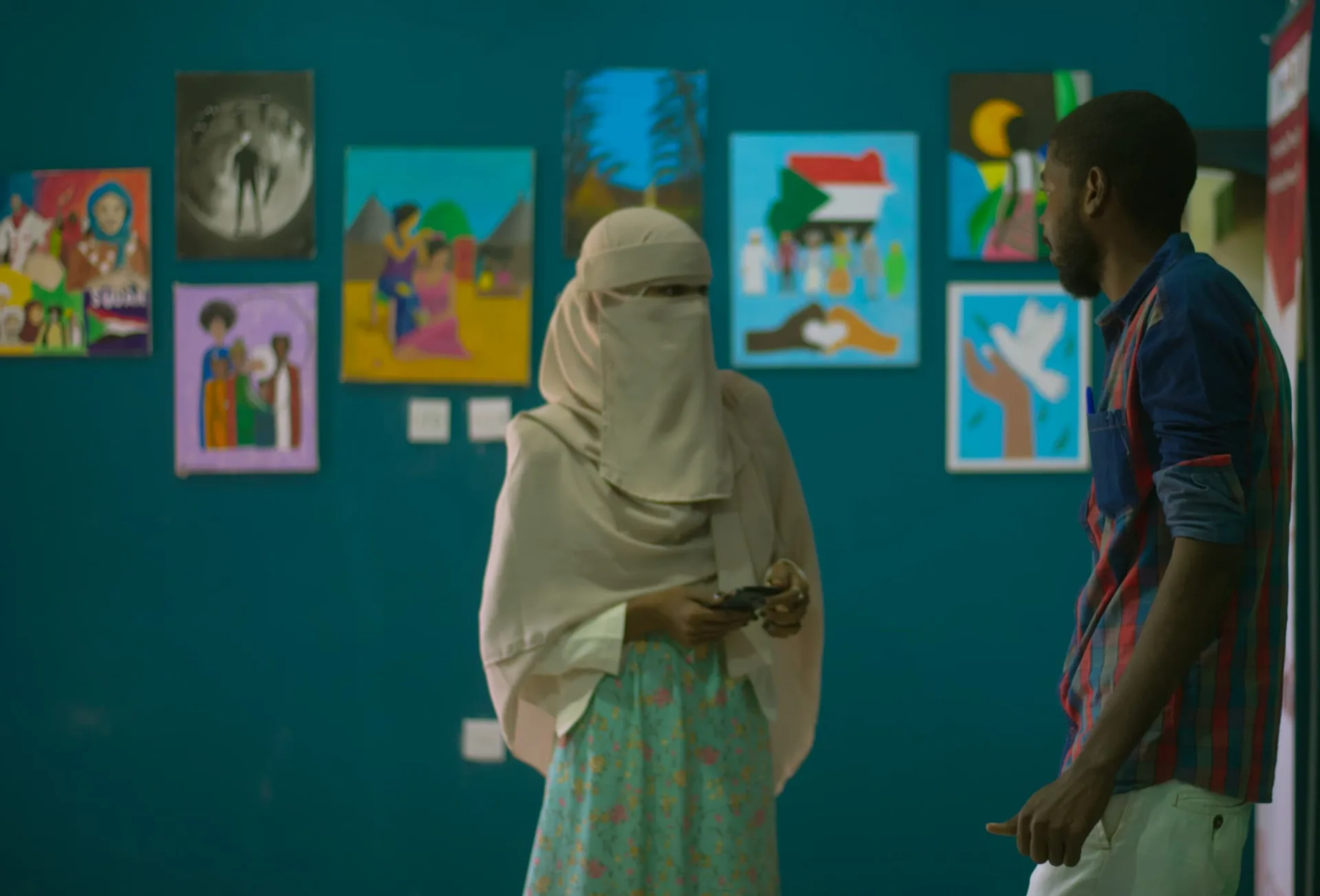 Audience filming a performance on their phones beside displayed artwork