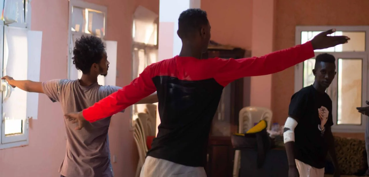Performers with their arms stretched wide during a movement exercise.