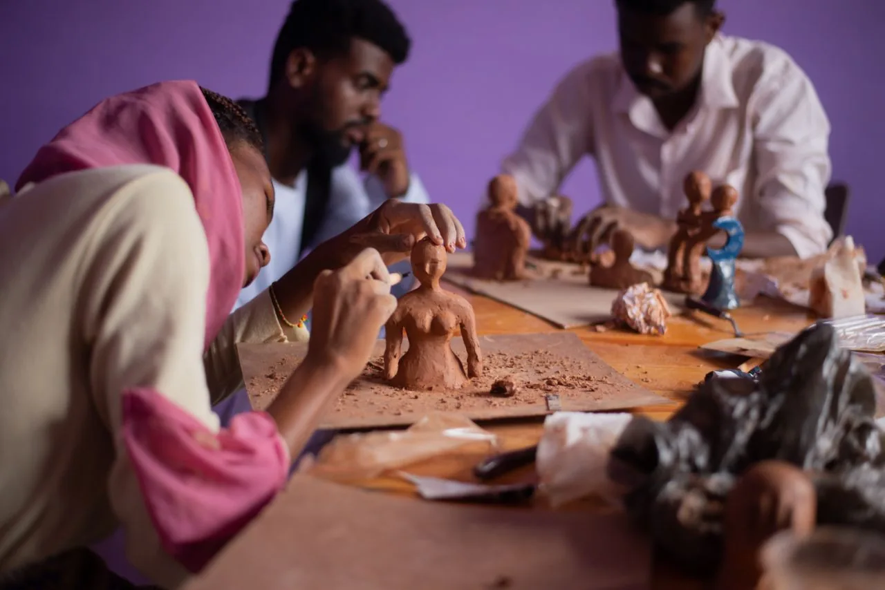 Human figures shaped from clay, drying on a workshop table.