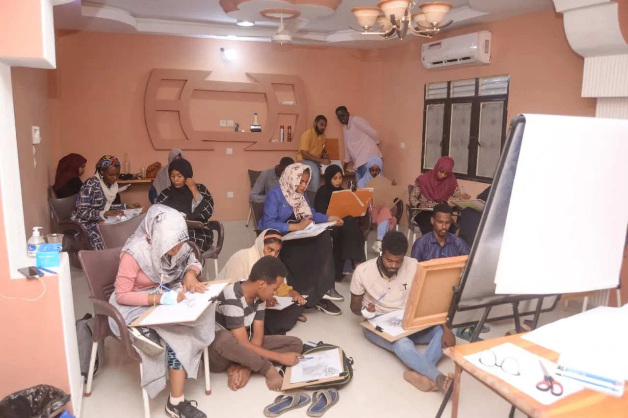 Participants working on drawings at long workshop tables.